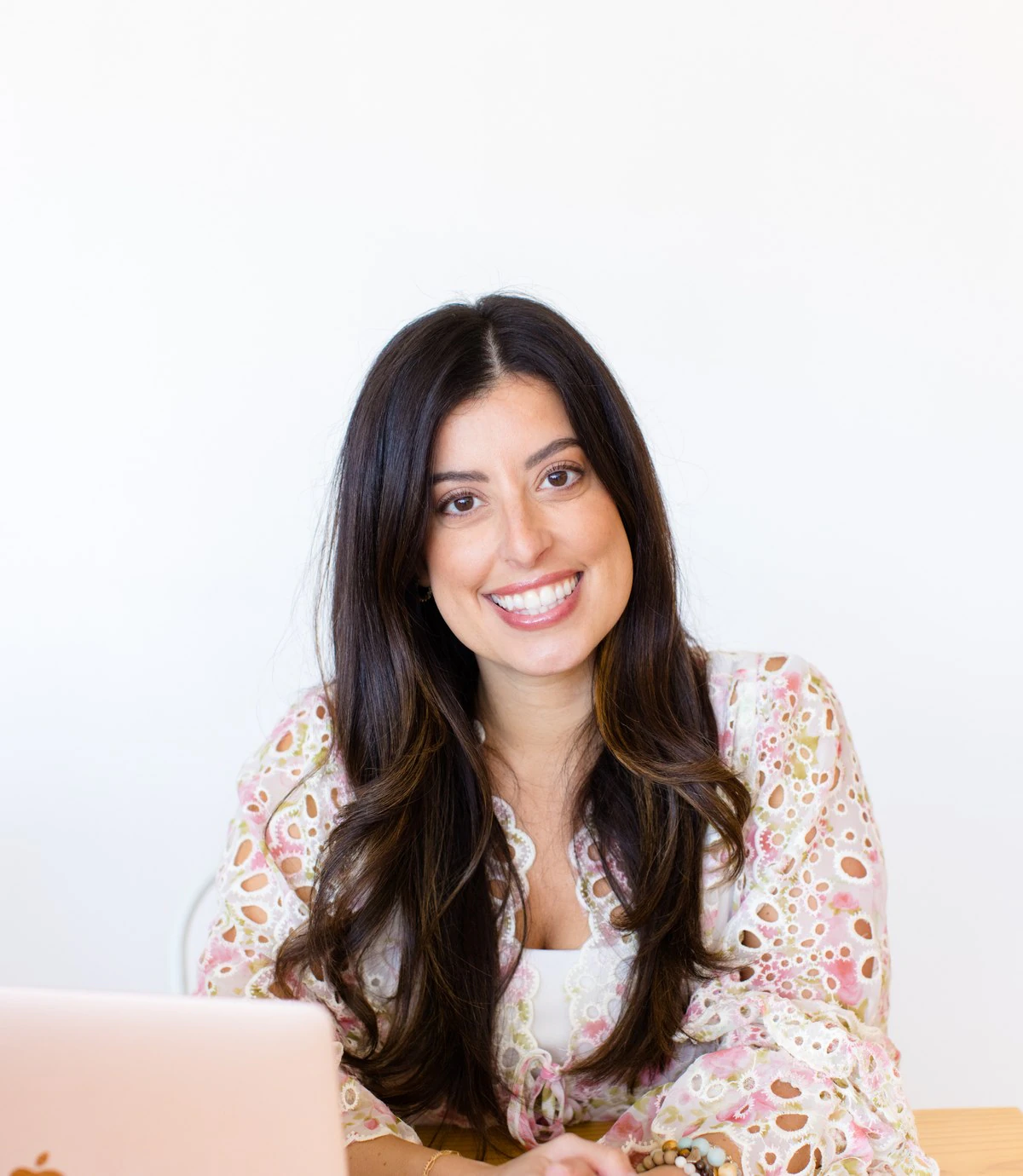 Alana Cummings smiling across the table, hands folded on her laptop.