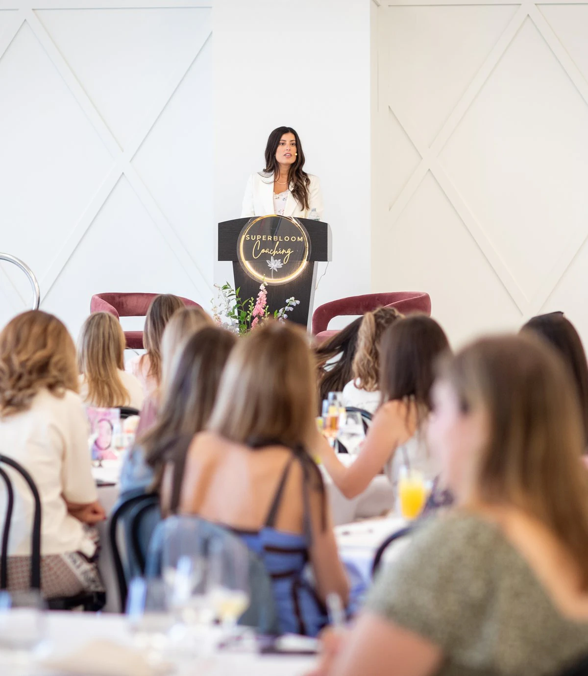 Alana Cummings speaking at the Superbloom podium to a full room.